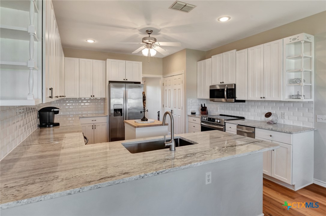 202 Prairie View Road Victoria, TX 77904 - Photo 9 of 47 a kitchen with stainless steel appliances kitchen island granite countertop a sink dishwasher stove and white cabinets with wooden floor