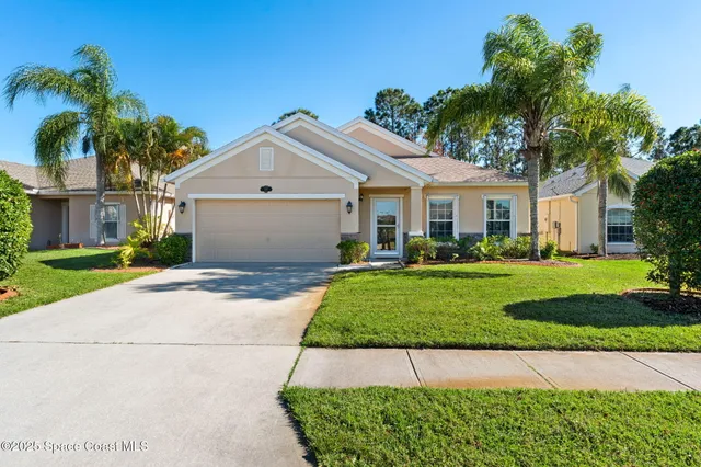 a front view of a house with a garden and palm trees