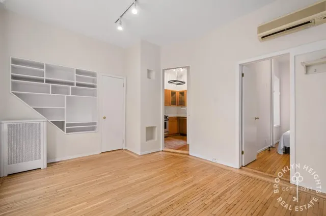 a view of an empty room with wooden floor and closet