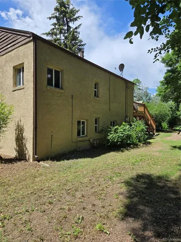 a view of a house with a big yard plants and large trees