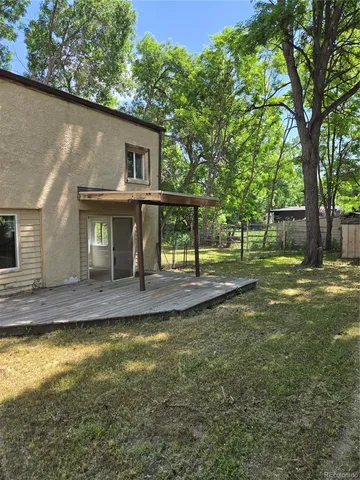 a view of a house with large tree and wooden fence