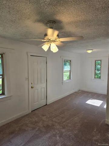 an empty room with windows and fan