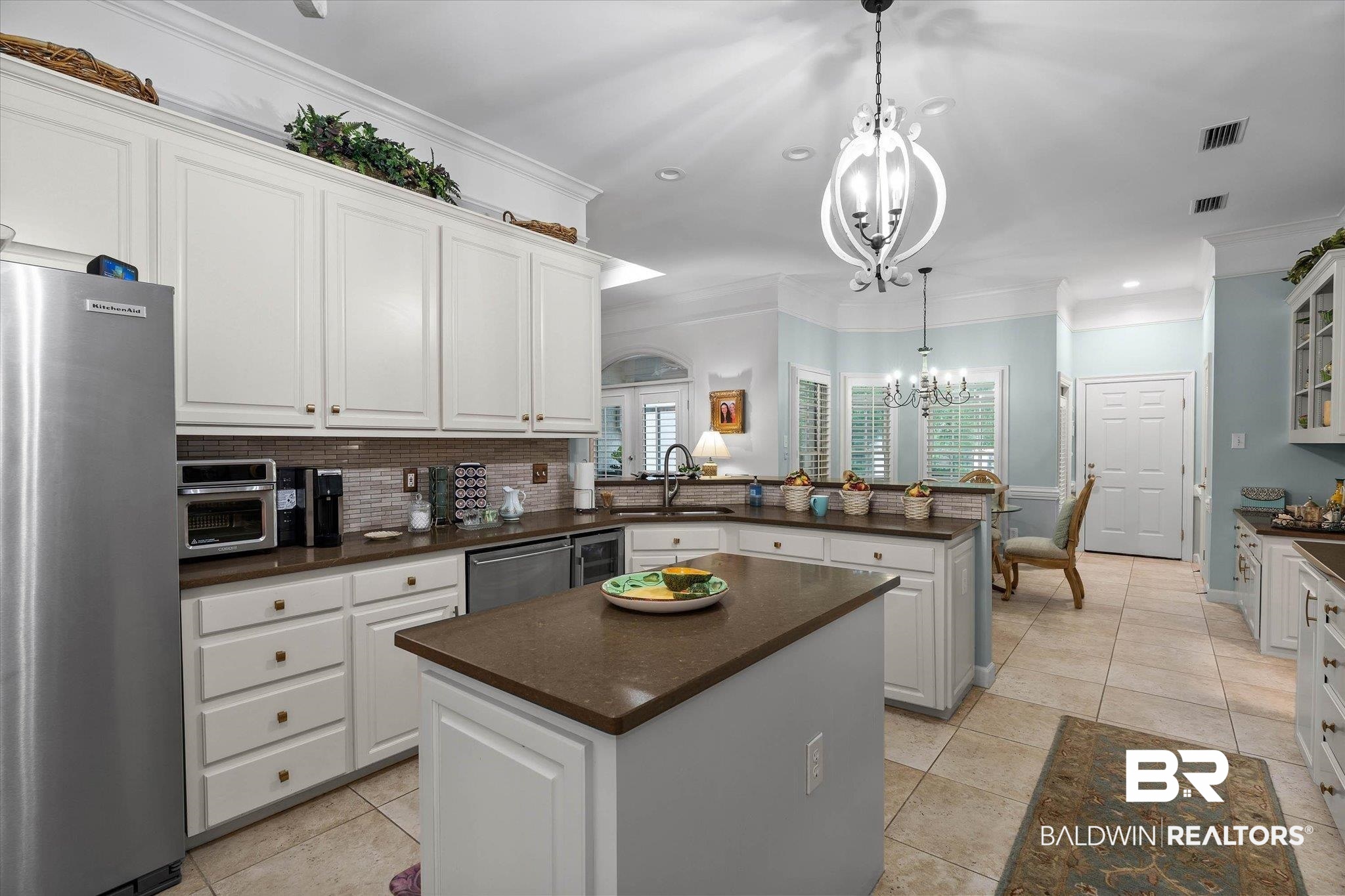 136 Old Mill Road Fairhope, AL 36532 - Photo 8 of 36 Spacious kitchen featuring an island with a solid surface countertop, white cabinetry with brass hardware, a tile backsplash, and tile flooring