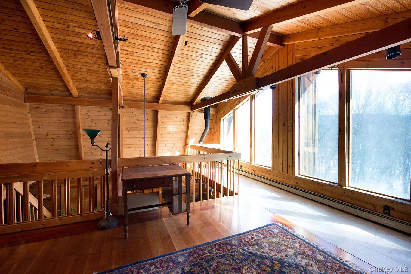 1644 Lakes Road Monroe, NY 10950 - Photo 23 of 50 Additional living space featuring baseboard heating, hardwood / wood-style floors, wood ceiling, wood walls, and vaulted ceiling with beams. Great spot to sit enjoy a book.