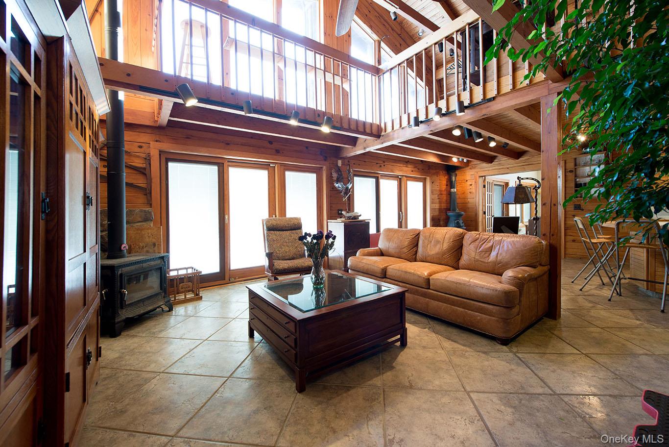 1644 Lakes Road Monroe, NY 10950 - Photo 7 of 50 Living area featuring a wood stove, wooden walls, and a high wooden beamed ceiling