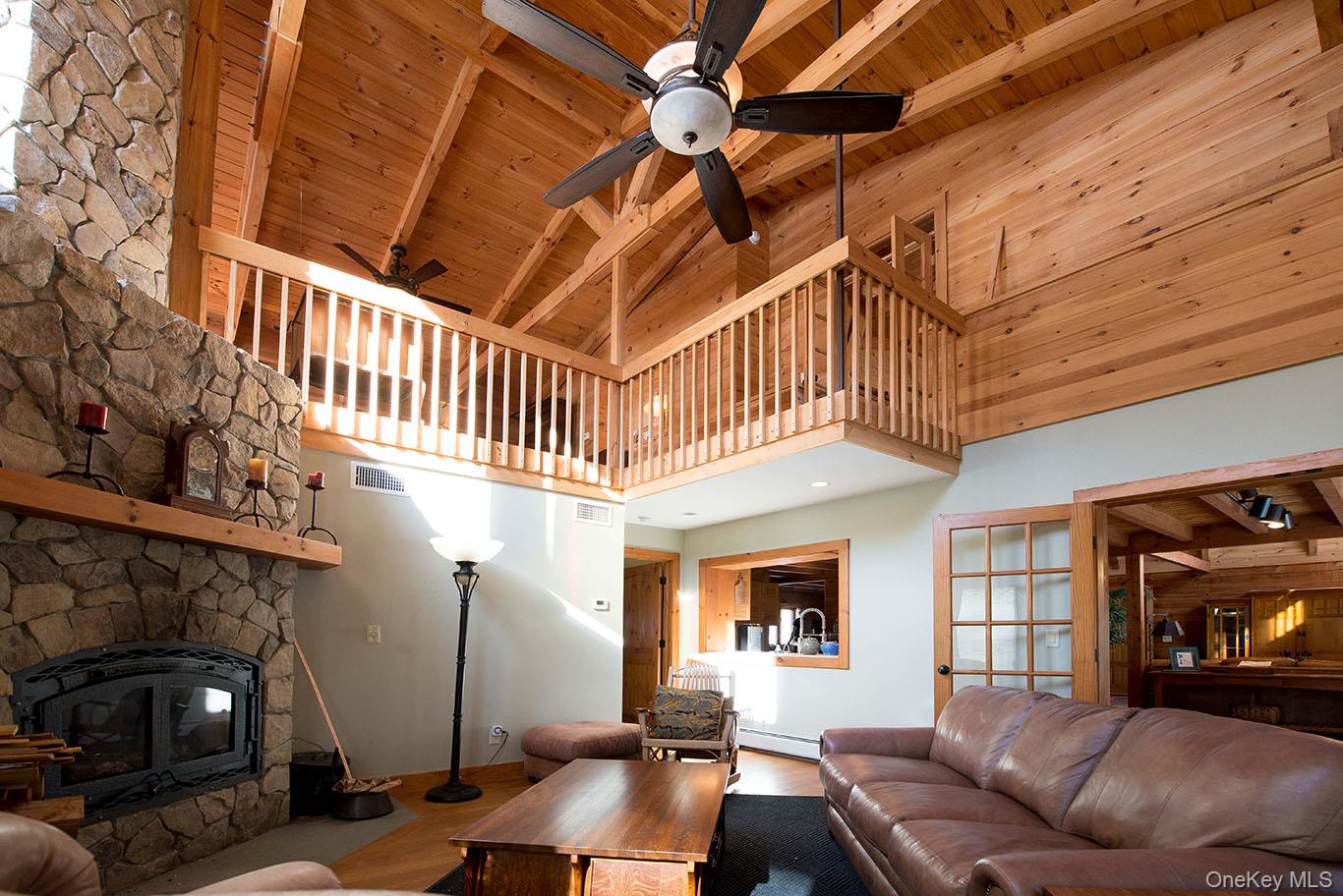 1644 Lakes Road Monroe, NY 10950 - Photo 9 of 50 Living area featuring a stone fireplace, wood finished floors, a high wood beamed ceiling, and baseboard heating