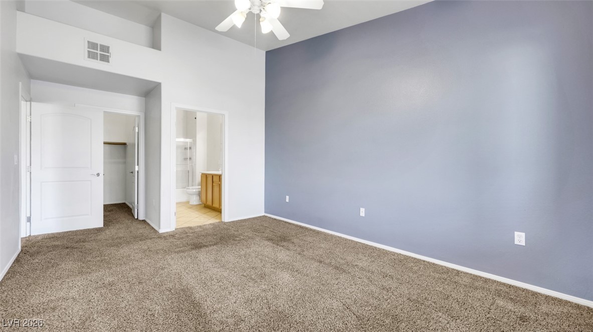 2305 West Horizon Ridge Parkway, Unit 1224 Henderson, NV 89052 - Photo 16 of 26 Unfurnished bedroom with a walk in closet, light carpet, ensuite bathroom, ceiling fan, and a towering ceiling