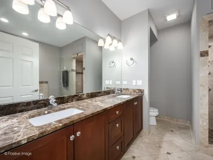 a bathroom with a granite countertop sink a toilet and a large mirror