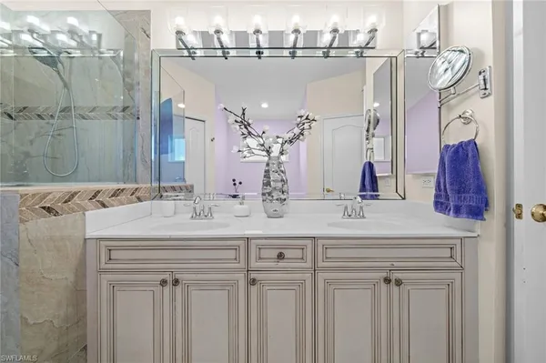 a bathroom with a sink a toilet a mirror and shower