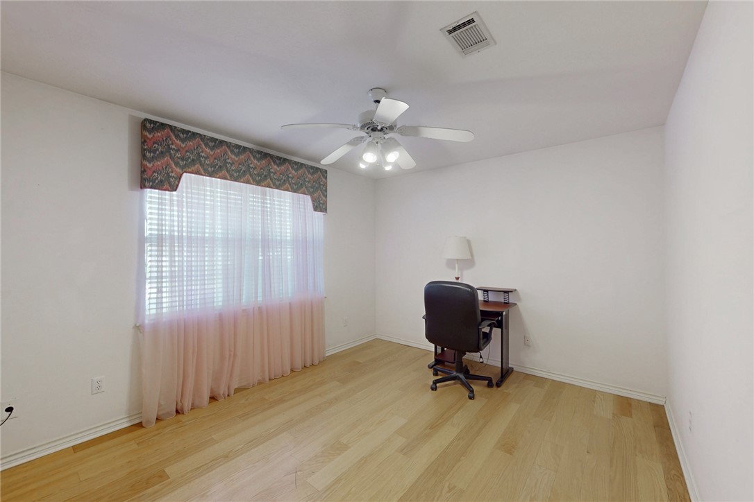 5901 Sheffield Terrace Lane Bryan, TX 77802 - Photo 18 of 31 Guest bedroom with ceiling fan and light kit, large closet, large windows allowing natural light and view of backyard, light laminate flooring
