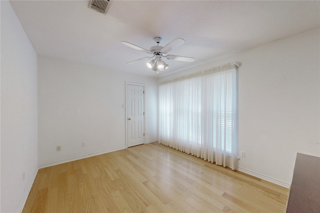 5901 Sheffield Terrace Lane Bryan, TX 77802 - Photo 23 of 31 Front guest bedroom with large walk-in closet, ceiling fan with light fixture, light laminate flooring, large windows allowing natural light-view of front yard