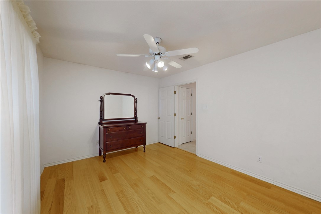 5901 Sheffield Terrace Lane Bryan, TX 77802 - Photo 24 of 31 Front guest bedroom with large walk-in closet, ceiling fan with light fixture, light laminate flooring, large windows allowing natural light-view of front yard