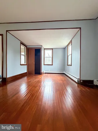 a view of an empty room with wooden floor and window