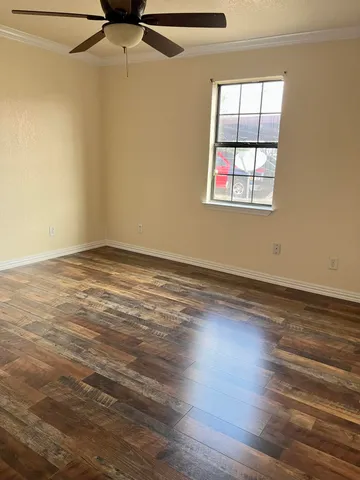 an empty room with wooden floor closet and windows