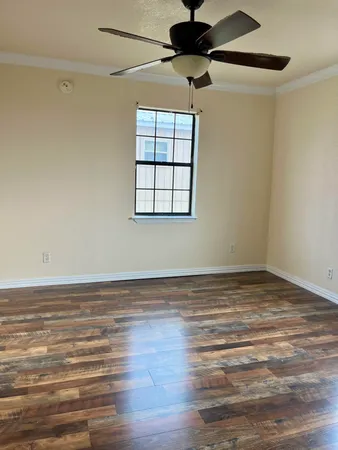 a view of a room with wooden floor a ceiling fan and a window