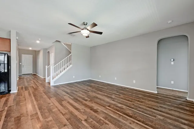 a view of an empty room with wooden floor and a chandelier