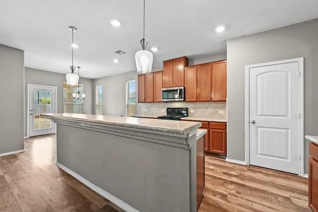 a large kitchen with granite countertop a large window and stainless steel appliances
