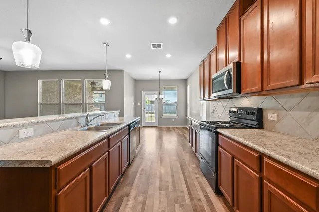 a kitchen with granite countertop center island wooden floor and stainless steel appliances