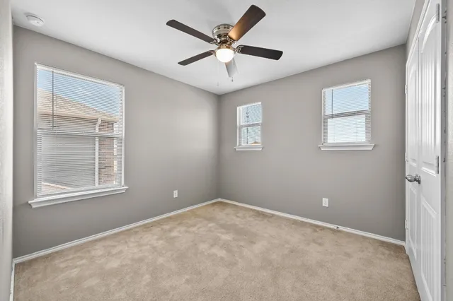 an empty room with windows and ceiling fan