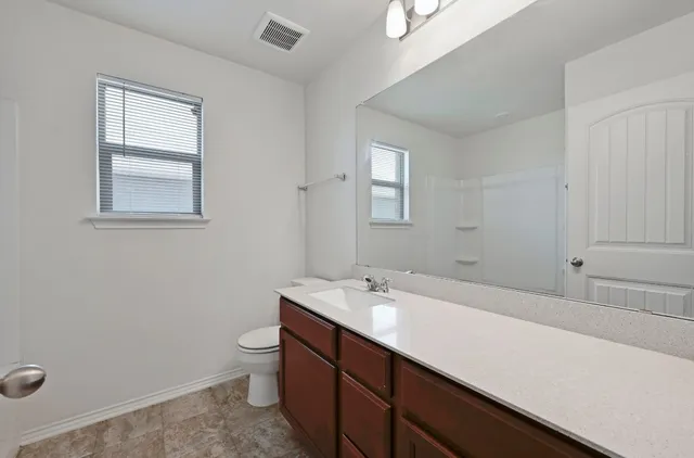 a bathroom with a sink a toilet and a window