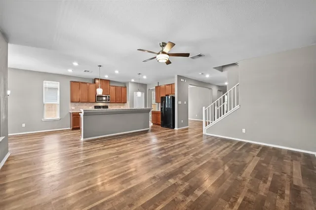 a view of a kitchen with a kitchen island wooden floor and a ceiling fan