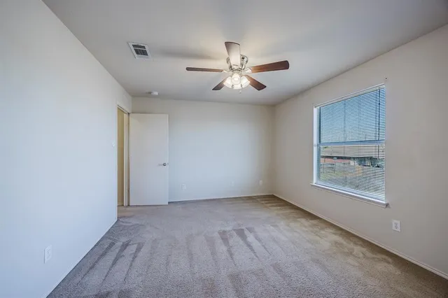 a view of an empty room with a window and a ceiling fan