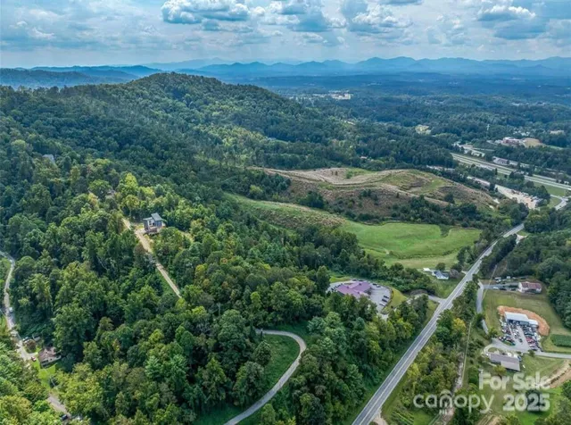 an aerial view of residential house with outdoor space and trees all around