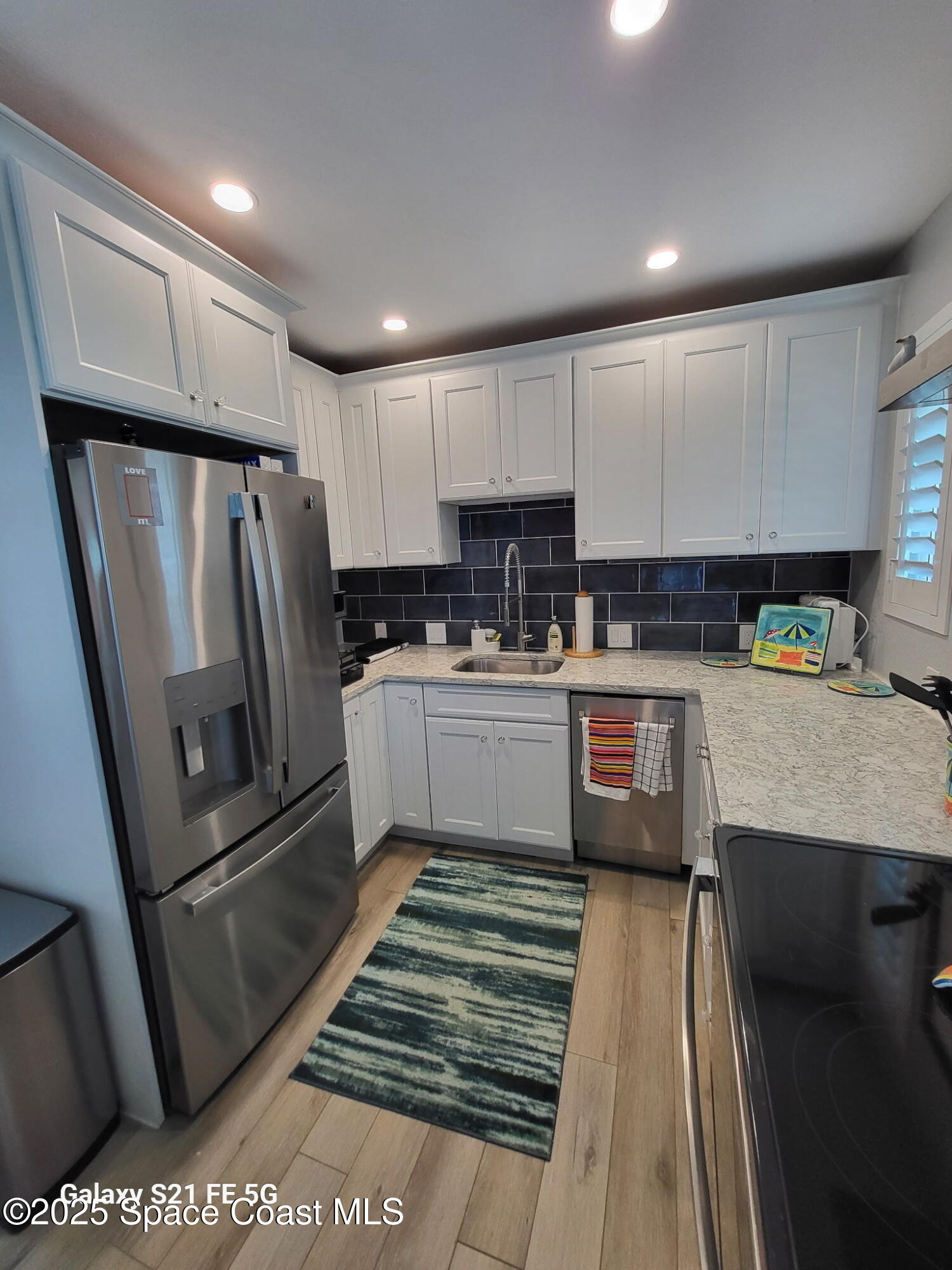 4000 Ocean Beach Boulevard, Unit 4F Cocoa Beach, FL 32931 - Photo 3 of 12 a kitchen with a refrigerator a sink and wooden cabinets
