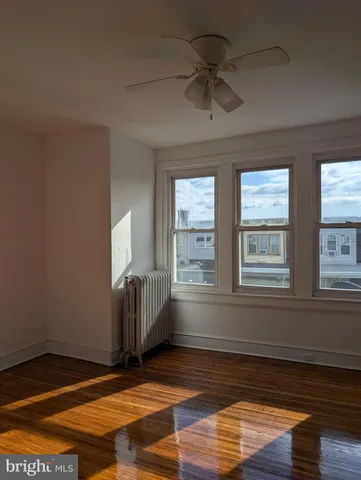 a view of an empty room with window and wooden floor