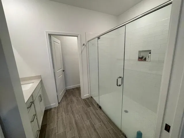 a bathroom with a shower and a wooden floor