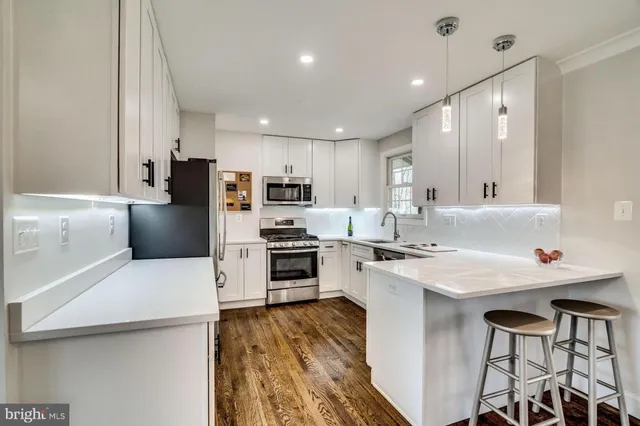 a kitchen with a sink a stove a refrigerator and white cabinets