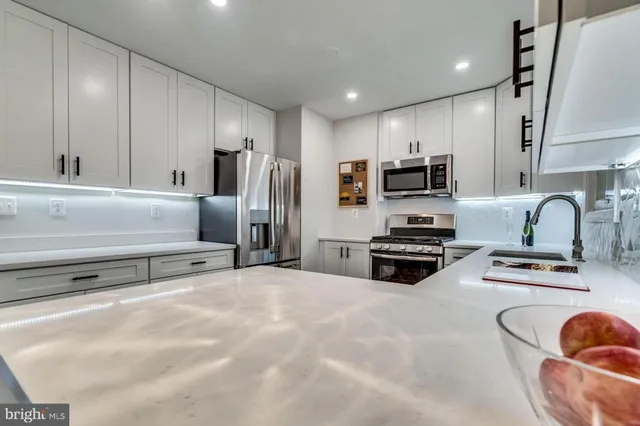 a kitchen with stainless steel appliances a stove a sink a refrigerator white cabinets and a refrigerator