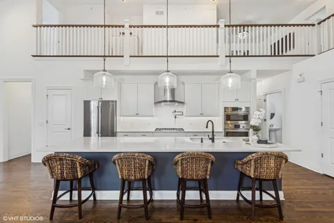 a kitchen with stainless steel appliances granite countertop a table chairs sink and cabinets