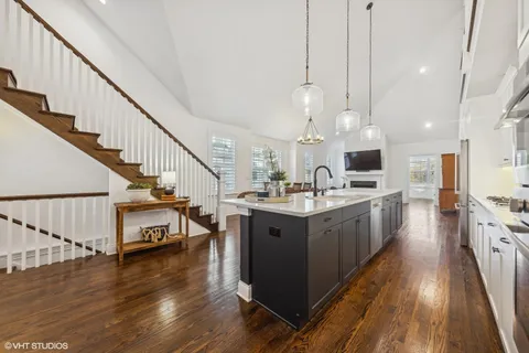 a kitchen with stainless steel appliances a stove top oven a sink dishwasher and a kitchen island with wooden floor