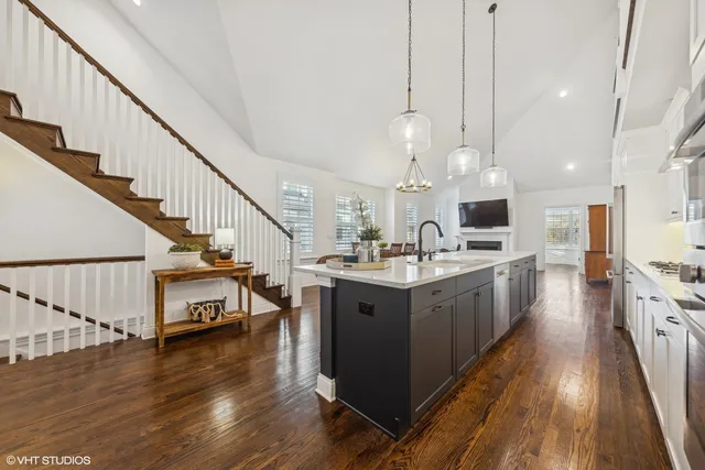 a kitchen with stainless steel appliances a stove top oven a sink dishwasher and a kitchen island with wooden floor