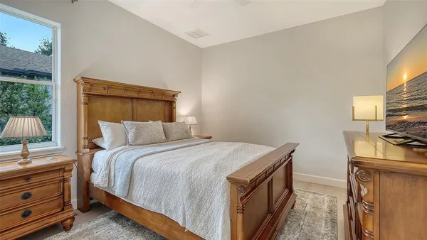 a bedroom with a bed and a flat tv screen on dresser