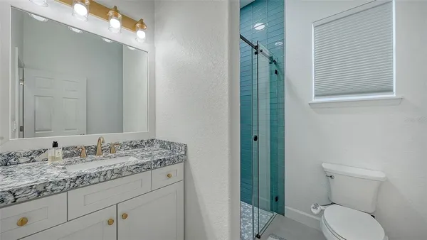 a bathroom with a granite countertop sink toilet and shower