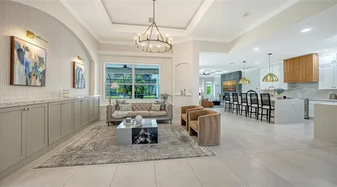 a living room with furniture a chandelier and a dining table