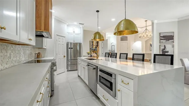 a large kitchen with stainless steel appliances granite countertop a sink a stove and a refrigerator
