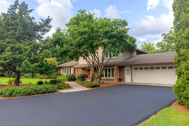 a front view of a house with a yard and trees