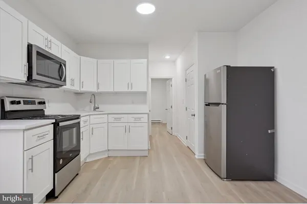 a kitchen with stainless steel appliances white cabinets and a refrigerator