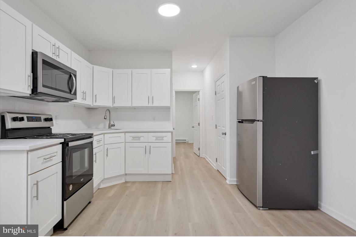 1999 Church Lane, Unit 1 Philadelphia, PA 19141 - Photo 4 of 10 a kitchen with stainless steel appliances white cabinets and a refrigerator