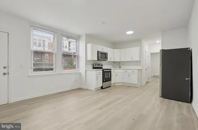 a kitchen with a refrigerator a stove top oven and white cabinets