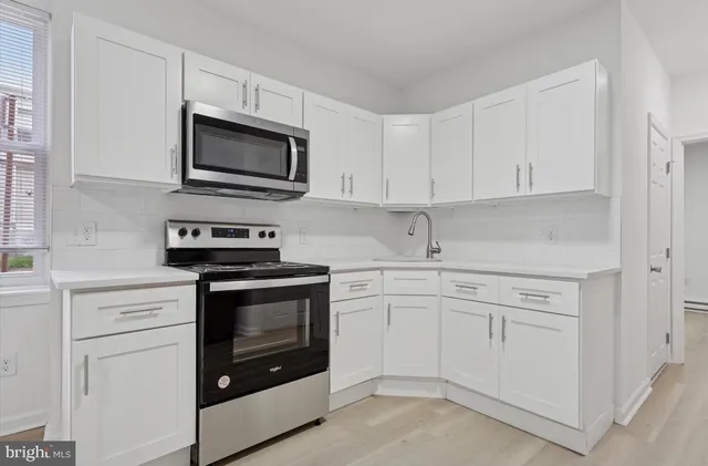 a kitchen with white cabinets and stainless steel appliances