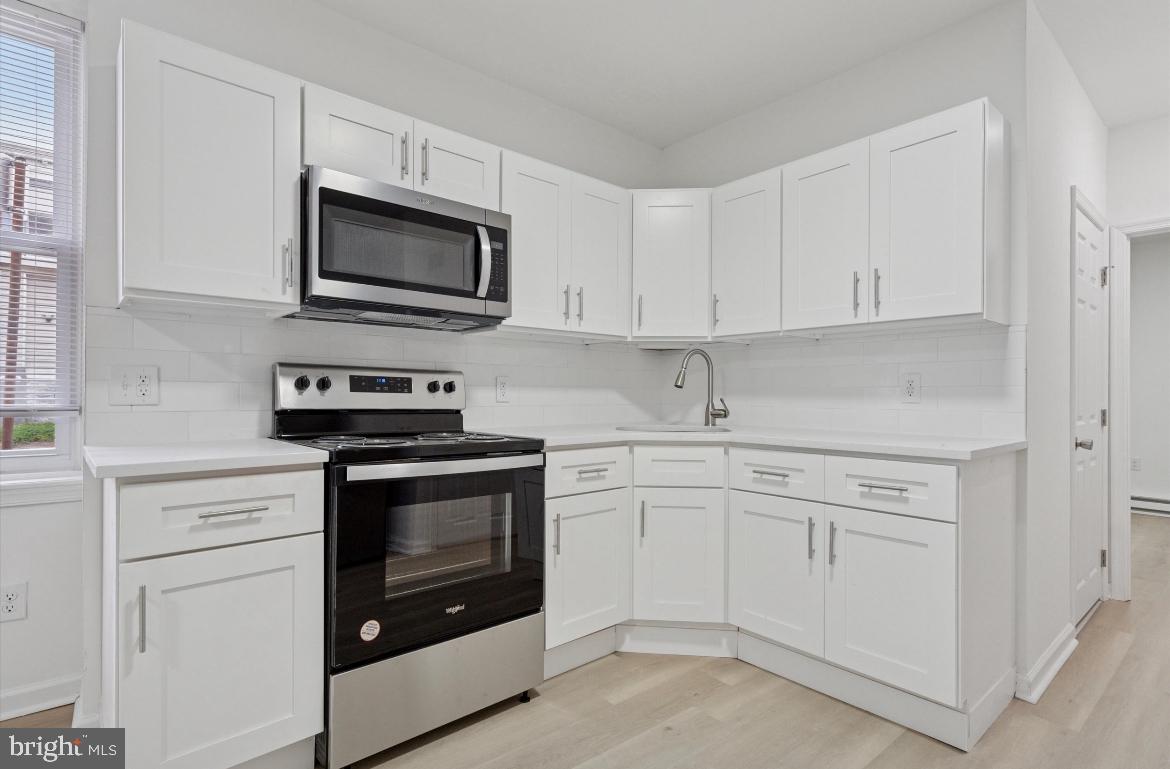 1999 Church Lane, Unit 1 Philadelphia, PA 19141 - Photo 6 of 10 a kitchen with white cabinets and stainless steel appliances
