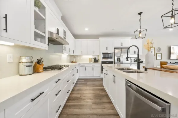 a kitchen with stainless steel appliances kitchen island granite countertop a dining table chairs and white cabinets