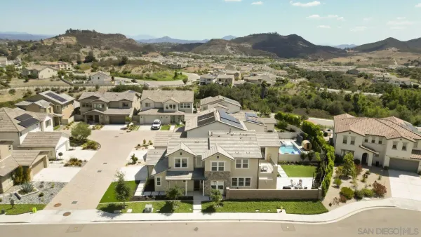 an aerial view of a residential houses with outdoor space and trees