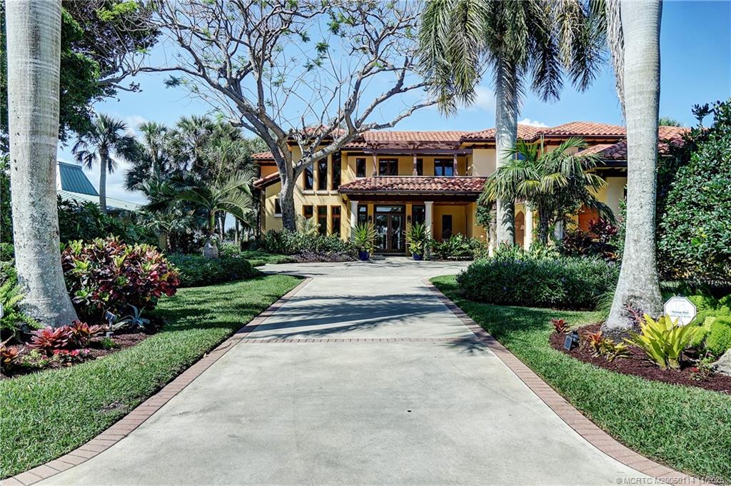 a front view of a house with a garden and palm trees