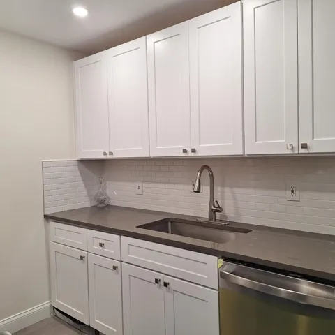 a kitchen with granite countertop white cabinets and a sink