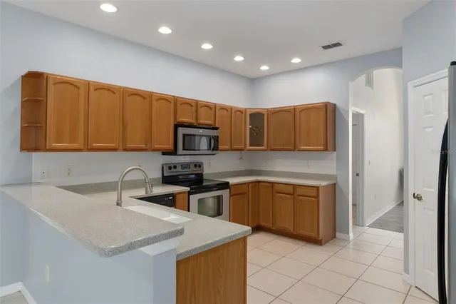 a kitchen with stainless steel appliances granite countertop a sink a stove a refrigerator a microwave oven with white cabinets